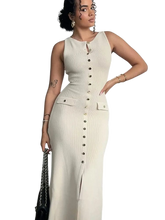 A woman wears a sleeveless, apricot-colored ribbed maxi dress with a button-down front and slit.