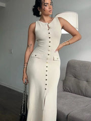 A woman wears a sleeveless, apricot-colored ribbed maxi dress with a button-down front and slit.