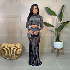 A woman wears a black two-piece long-sleeve dress featuring sheer mesh fabric and rhinestone details.