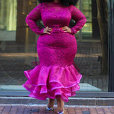 A woman wears a long-sleeved, fuchsia lace mermaid dress with a ruffled organza hem.