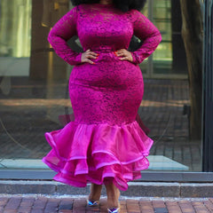A woman wears a long-sleeved, fuchsia lace mermaid dress with a ruffled organza hem.