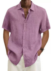 A man wears a short-sleeved, loose-fit mauve cotton linen button-down shirt.