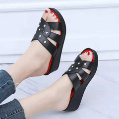 A pair of black wedge sandals with rhinestone-embellished straps and a red insole.
