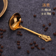 A gold-colored stainless steel soup ladle with an ornate relief pattern on the handle.