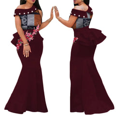 A burgundy off-the-shoulder mermaid dress featuring a patterned bodice, pearl accents, and floral applique.