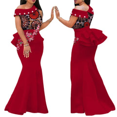 A woman models a red floor-length mermaid dress featuring an African print bodice, pearl accents, and floral applique.