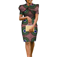 A woman wears a knee-length African print pencil dress with a matching cape and a straw handbag.