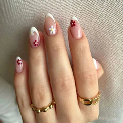 Almond-shaped press-on nails with a French tip and small floral accents on a nude base.