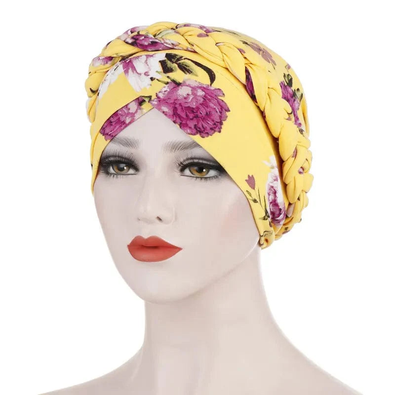 A yellow floral print turban cap featuring a braided headband detail worn by a mannequin.