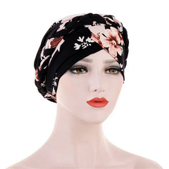 A mannequin wears a black cotton turban featuring a floral pattern and a braided headband detail.