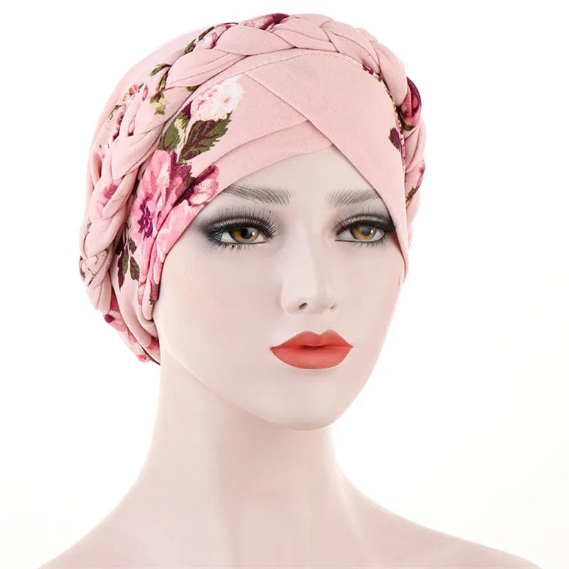A mannequin wears a light pink floral turban with a braided headband detail.