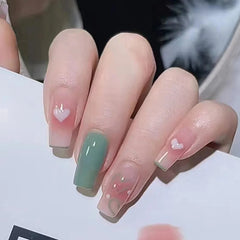 A set of mid-length coffin-shaped press-on nails featuring a mix of green and pink heart designs.