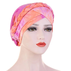 A mannequin wears a pink and orange tie-dye cotton turban featuring a decorative braided headband.
