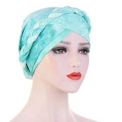 A mannequin wears a light blue and white tie-dye cotton turban with a braided headband detail.