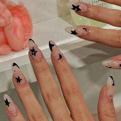 Mid-length almond-shaped press-on nails featuring a nude base with black star and moon accents.