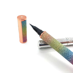A waterproof adhesive eyeliner pen with a glittery rainbow gradient finish and a black tip.