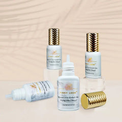 Four bottles of Pinky Leem banana scented eyelash extension glue with gold textured caps.