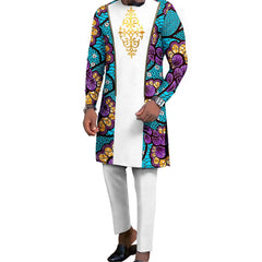 A man wears a white long-sleeved tunic with patterned blue and purple side panels and matching white trousers.