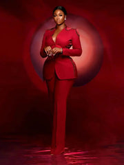 A woman wears a red two-piece suit featuring a V-neck jacket with beaded shoulder and side details.