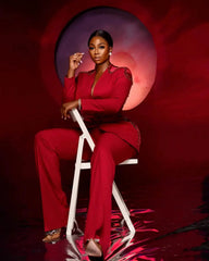 A woman wears a red two-piece suit featuring a single-breasted V-neck jacket with beaded details.