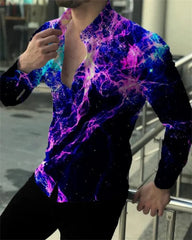 A man wears a long-sleeved button-down shirt featuring a vibrant purple and blue nebula print.