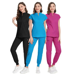 Three women wearing matching scrub sets in black, blue, and pink with jogger-style pants.