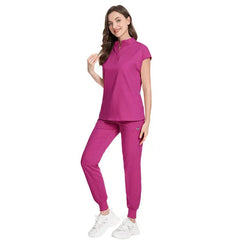 A woman wears a magenta scrub set with a short-sleeved top and jogger-style pants.