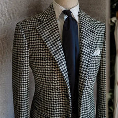 A men's black and white houndstooth blazer featuring a notched lapel and single-breasted closure.