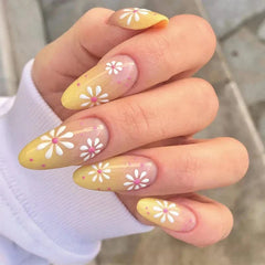 Long almond-shaped press-on nails with a yellow gradient base and white daisy flower designs.