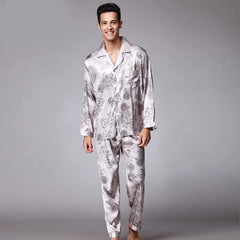 A man wears a light grey long-sleeved pajama set with a dark floral pattern.