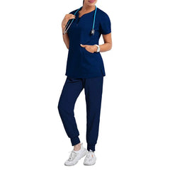 A woman wears a navy blue short-sleeve scrub top and matching jogger-style pants.