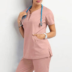 A woman wears a dusty pink short-sleeved scrub top and matching pants with a stethoscope.