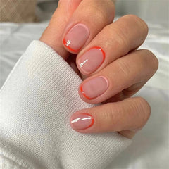 Short square press-on nails with a nude base and a thin orange French tip design.