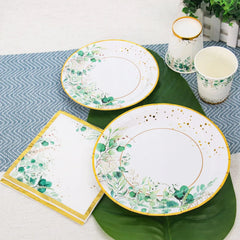 A set of disposable paper plates, cups, and napkins featuring a sage green leaf and gold rim design.