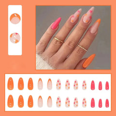 A set of twenty-four almond-shaped press-on nails featuring orange, pink, and heart-patterned designs.