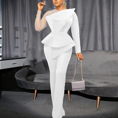 A white long-sleeved jumpsuit with a beaded sheer sleeve and a structured peplum waist.