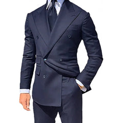 A man wears a dark navy blue double-breasted suit jacket with a matching tie and white shirt.