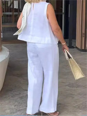 A woman wears a white sleeveless cotton linen blouse and matching wide leg pants.