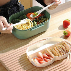 A green and white double-layer bento box filled with various foods, including noodles, shrimp, and fruit.