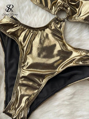 A metallic gold hollow-out bodysuit with a high-cut leg design on a white faux fur background.