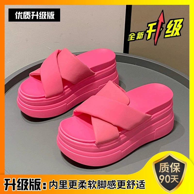 A pair of bright pink platform sandals with thick crisscross straps and a high muffin heel.