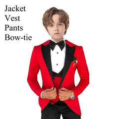 A boy wears a red tuxedo jacket with black lapels, a black vest, and a black bow tie.