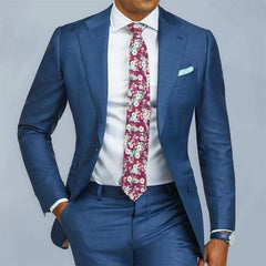 A man wears a slim fit blue two-piece suit with a white shirt and a floral patterned tie.