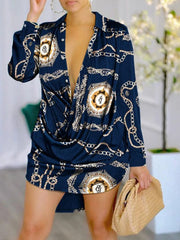 A woman wears a navy blue long-sleeve mini shirt dress featuring a gold chain and letter print.