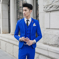 A man wears a slim-fit royal blue three-piece suit with a white shirt and patterned tie.