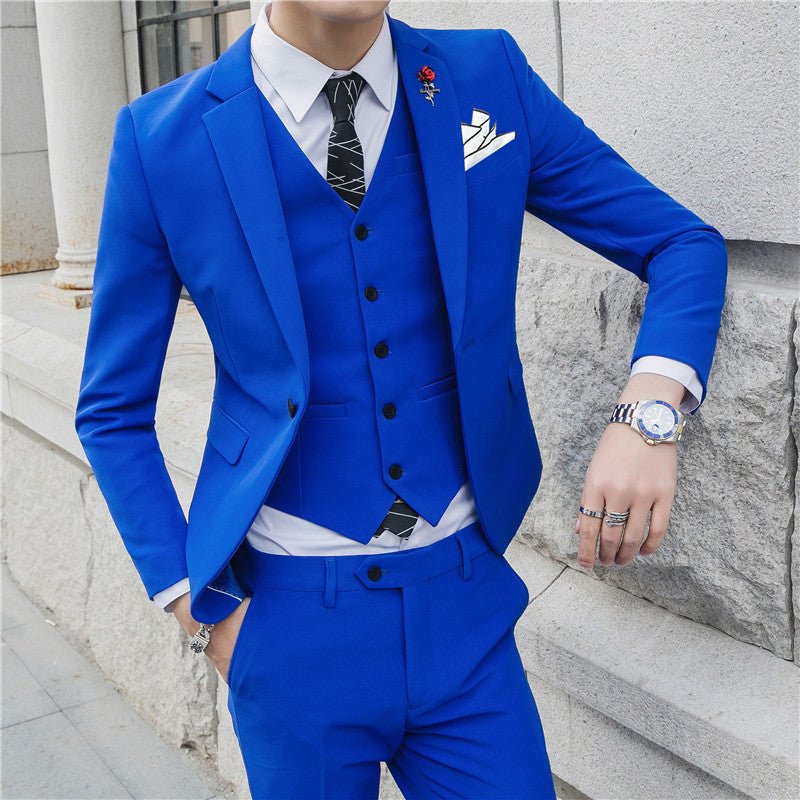 A man wears a slim-fit royal blue three-piece suit with a white shirt and patterned tie.