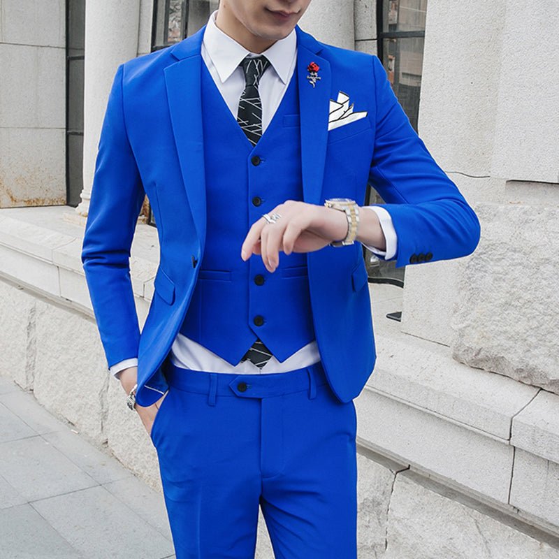 A man wears a slim-fit royal blue three-piece suit with a white shirt and patterned tie.