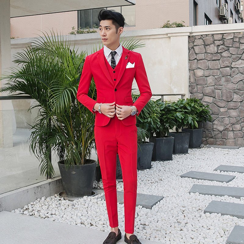 A man wears a slim-fit red three-piece suit with a white shirt and patterned tie.