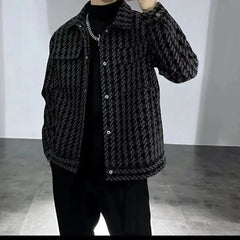 A man wears a black and grey houndstooth patterned jacket with a square collar and button front.