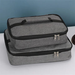 Two gray rectangular insulated lunch bags with black trim and double zippers stacked on a table.